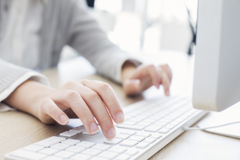 Bild: Ein Mensch schreibt mit den Händen auf einer Computer Tastatur.